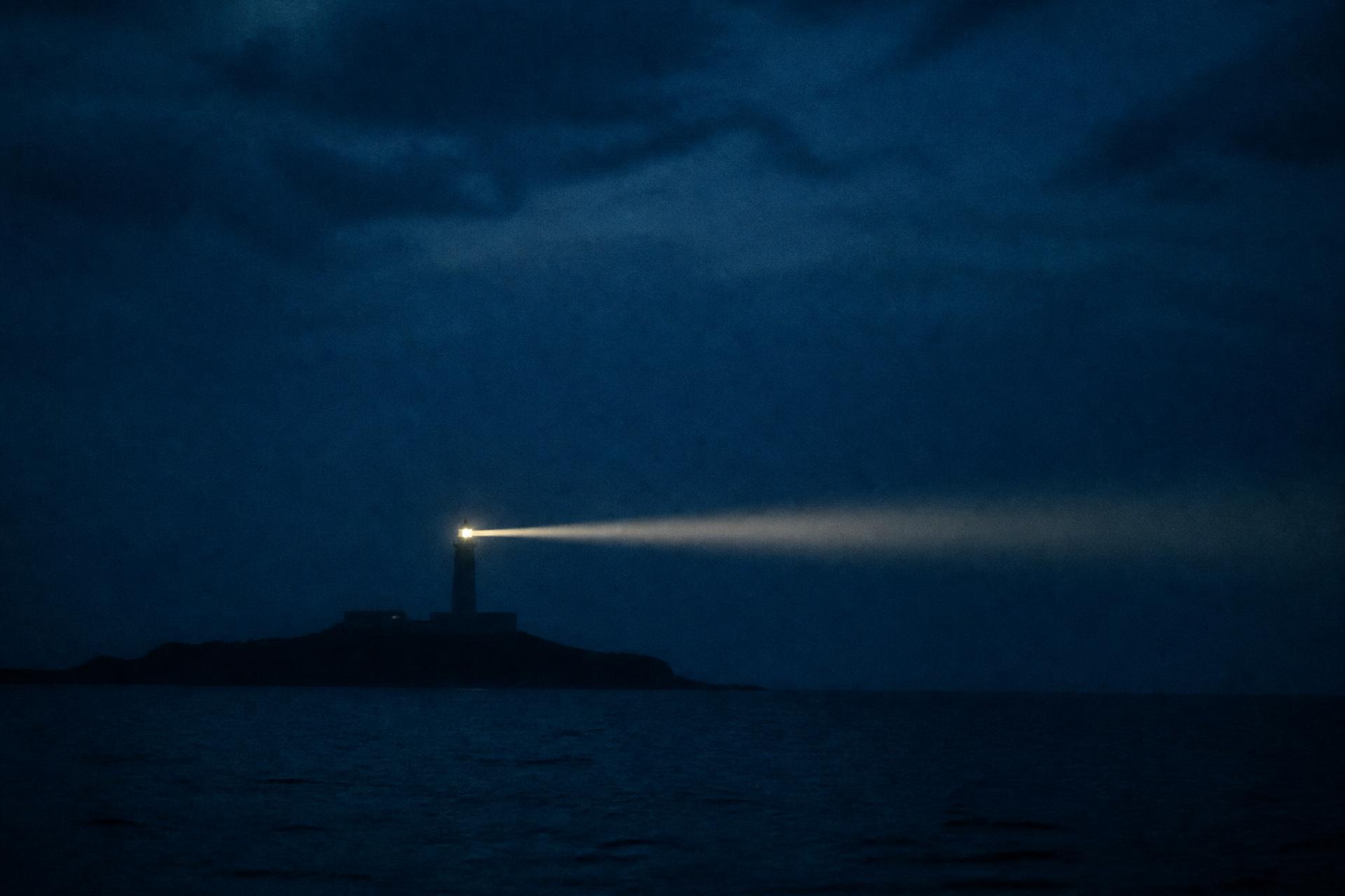 Faro en la noche proyectando su luz hacia el horizonte